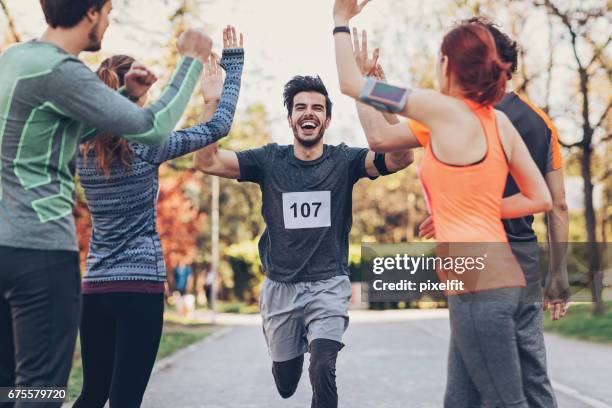 groep van atleten groet de winnaar bij de finse lijn - finishing stockfoto's en -beelden