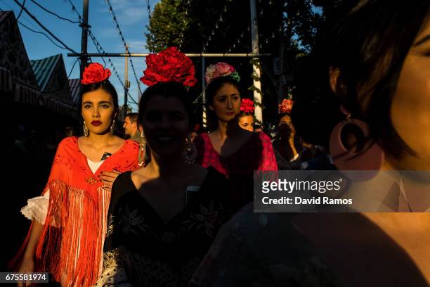 Women wearing traditional Sevillana dresses enjoy the atmosphere at the Feria de Abril on May 1, 2017 in Seville, Spain. The Feria de Abril, which...
