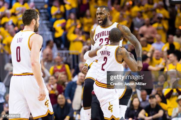 LeBron James celebrates with Kyrie Irving and Kevin Love of the Cleveland Cavaliers after scoring during the first half of Game One of the NBA...