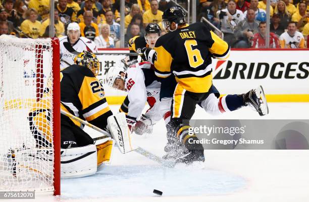 Andre Burakovsky of the Washington Capitals tries to get a shot off on goalie Marc-Andre Fleury of the Pittsburgh Penguins while taking a check from...
