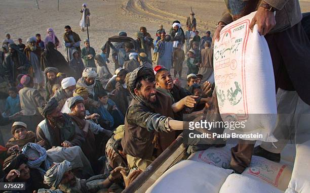 Afghan refugees at the Kili Faizo refugee camp desperately reach for bags of rice and sugar being handed out by a local aid organization December 4,...
