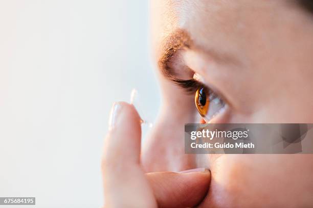 close up of woman putting in contact lens. - lenti a contatto foto e immagini stock
