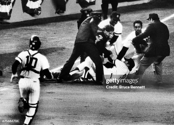 Catcher Rick Cerone of the New York Yankees runs to third base to help teammates Dave Winfield and Graig Nettles and umpires Al Clark and Mike Reilly...