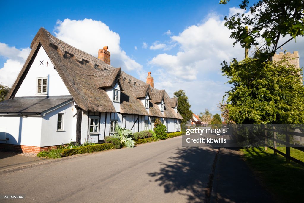 Quiet Suffolk quaint traditional village street Church and houses in spring sun with clouds