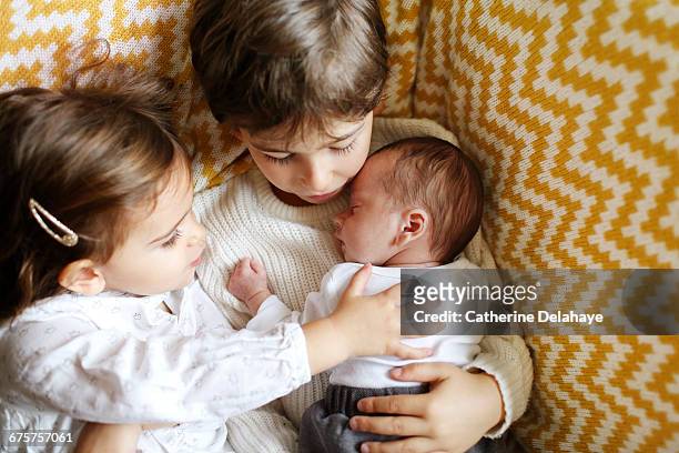 a baby in the arms of his big brother and sister - baby pullover stockfoto's en -beelden