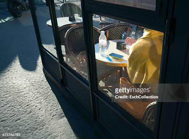 woman smoking a cigarette at brasserie in paris - tobacco product stock photos et images de collection