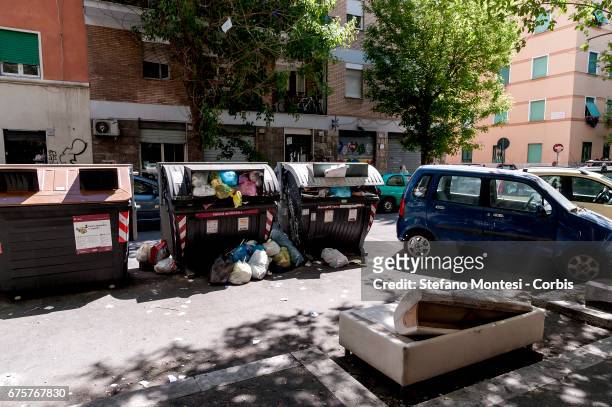 Wastes bins overflow and a sofa lies in the street in Torpignattara neighborhood on May 1, 2017 in Rome, Italy.