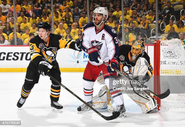 Olli Maatta skates alongside Boone Jenner of the Columbus Blue Jackets in front of Marc-Andre Fleury of the Pittsburgh Penguins in Game Five of the...