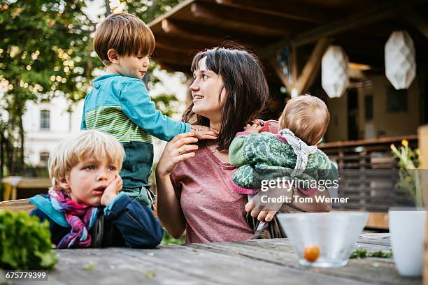 young mother with children sitting in a community - family with three children fotografías e imágenes de stock