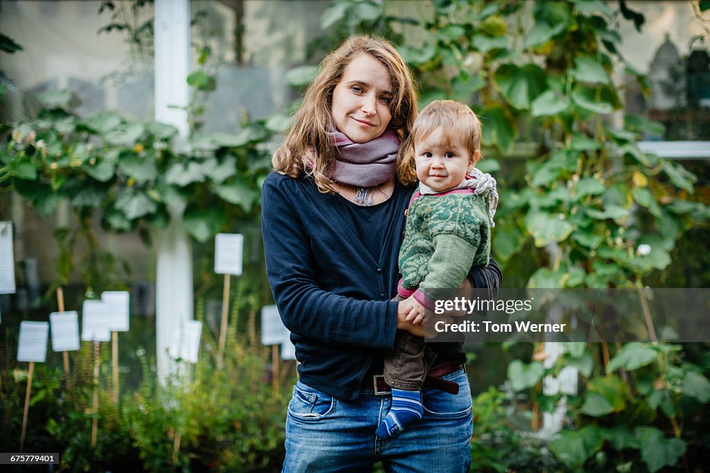 Mother with her child standing in community garden