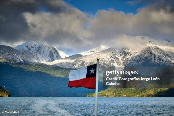 chilean flag against the mountains from the catamaran desk during the winterandean lake crossing - luz del sol stock pictures, royalty-free photos & images