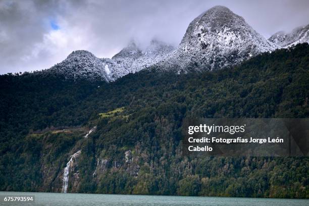 the waterfall of the lake view with clouds and snow over de mountain during the winter andean lake crossing - destinos turísticos stock pictures, royalty-free photos & images