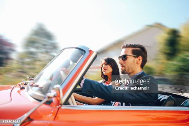 young fashionable couple in an oldtimer convertible sportscar - man driving sports car stock pictures, royalty-free photos & images