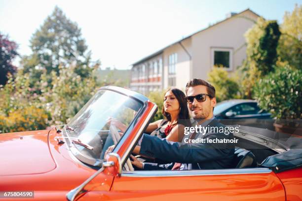 young fashionable couple in an oldtimer convertible sportscar - man driving sports car stock pictures, royalty-free photos & images