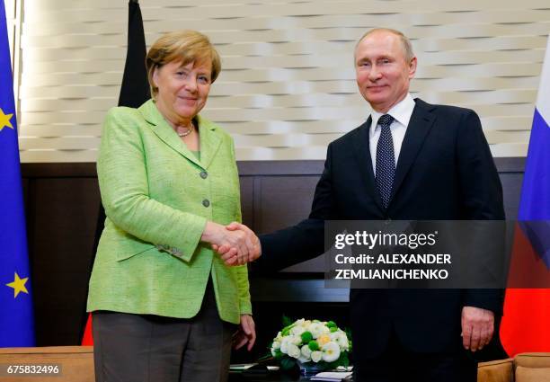 Russian President Vladimir Putin shakes hands with German Chancellor Angela Merkel during a meeting at the Bocharov Ruchei state residence in Sochi...