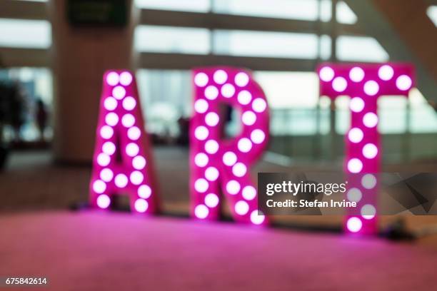 Soft-focus image of an illuminated sign which says "ART" welcomes visitors to an art fair in Hong Kong.