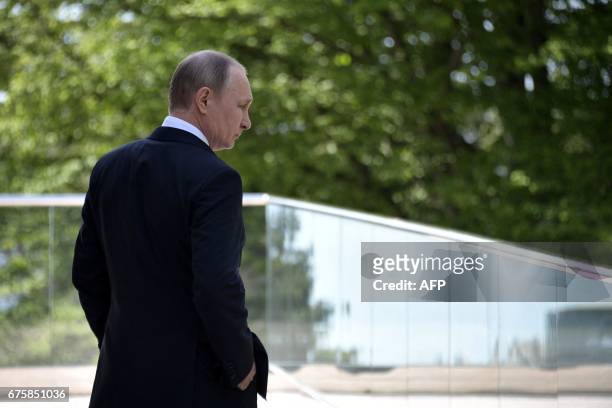 Russian President Vladimir Putin looks on as he waits for the arrival of German Chancellor ahead of their meeting at the Bocharov Ruchei state...