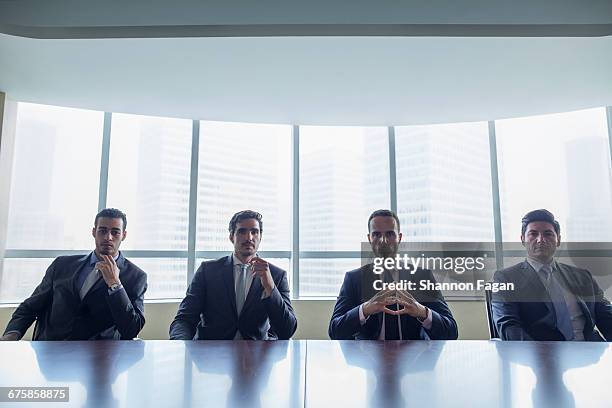 row of businessmen sitting at conference table - bussines group suit tie stock pictures, royalty-free photos & images