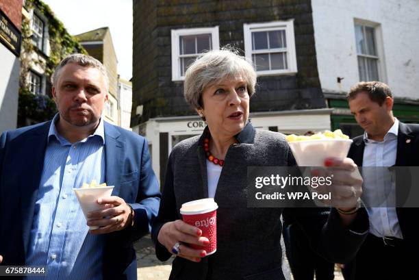 Britain's Prime Minister Theresa May enjoys some chips during a campaign stop on May 2, 2017 in Mevagissey, Cornwall, England. The Prime Minister is...