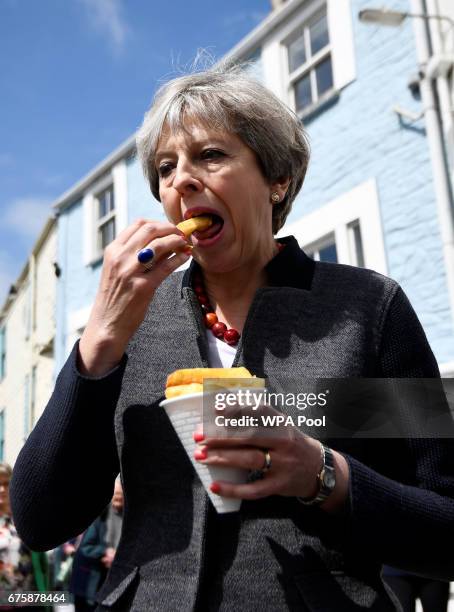 Britain's Prime Minister Theresa May enjoys some chips during a campaign stop on May 2, 2017 in Mevagissey, Cornwall, England. The Prime Minister is...