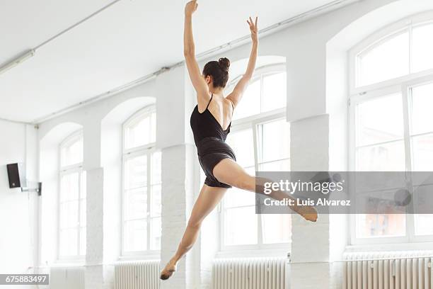 female ballet dancer jumping in mid-air at studio - estúdio de ballet imagens e fotografias de stock