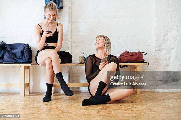 smiling friends using phone and sitting at studio - estúdio de ballet imagens e fotografias de stock
