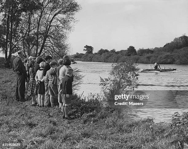 Watched from the riverbank by teachers and pupils from the local Riverside school, Captain, First Lieutenant Forbes stands on the deck of the Royal...