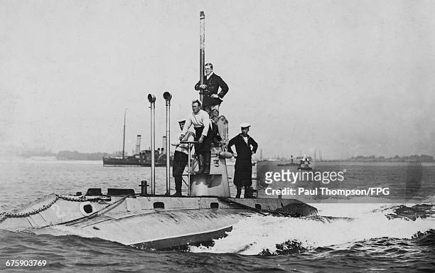 Officers and crew stand on deck around the conning tower of the second Royal Navy Holland-class submarine HMS Holland 2 on patrol entering Fort...