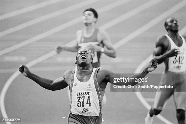 English sprinter John Regis, competing for Great Britain, throws his arms in the air in celebration after crossing the finish line in first place to...