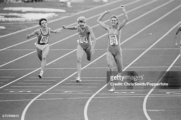 East German athlete Katrin Krabbe, competing for the German Democratic Republic, throws her arms in the air in celebration as she crosses the finish...