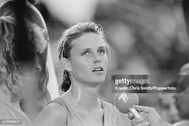 East German athlete Katrin Krabbe, competing for the German Democratic Republic, is interviewed by reporters after finishing in first place ahead of...