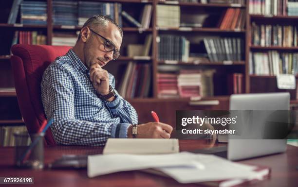 male manager taking notes in home office. - teachers desk books stock pictures, royalty-free photos & images