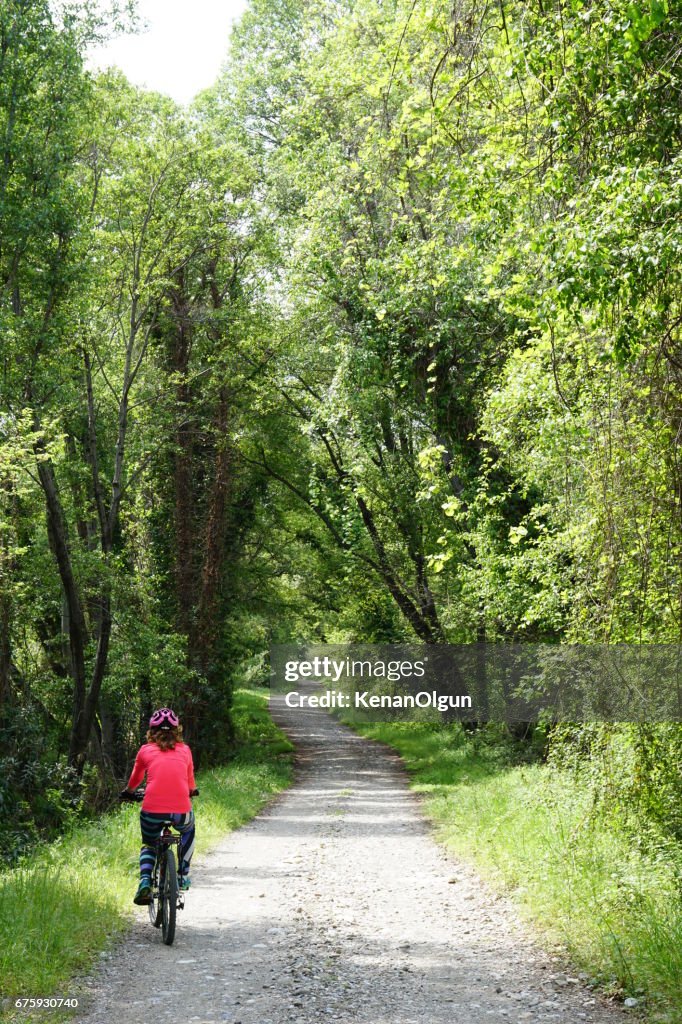 Woman riding bicycle on the forest road