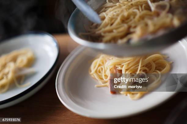 dishing up spaghetti - 麺 stockfoto's en -beelden