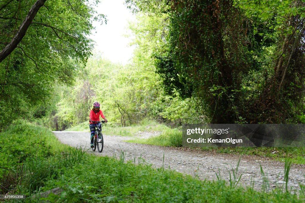 Woman riding bicycle on the forest road