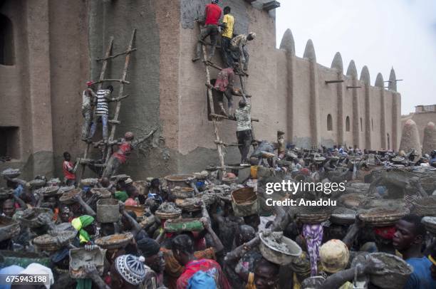 People carry their pots filled with Mud to restore Great Mosque of Djenne in Mali on April 30, 2017. The Great Mosque of Djenne listed in UNESCO as a...