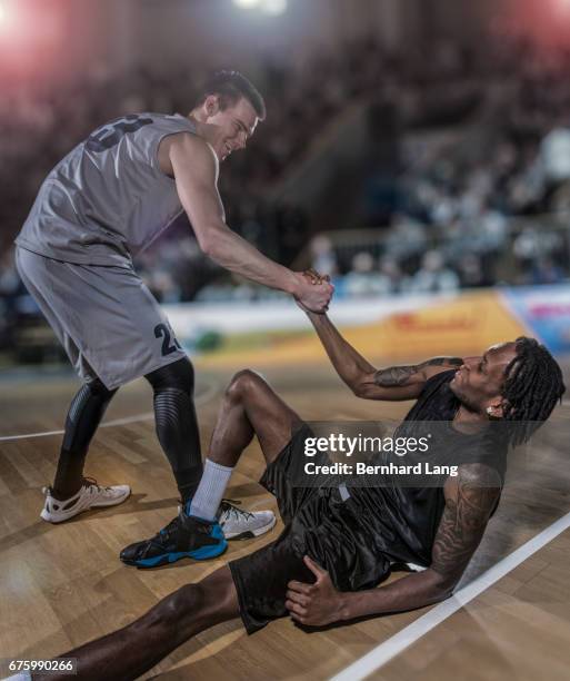 basketball player helping up his oponent - sportmannschaft stock pictures, royalty-free photos & images