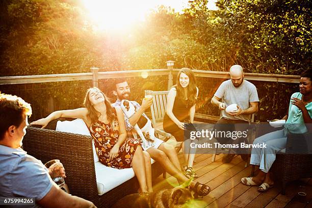 laughing group of friends eating dinner on deck - fiesta de jardín fotografías e imágenes de stock