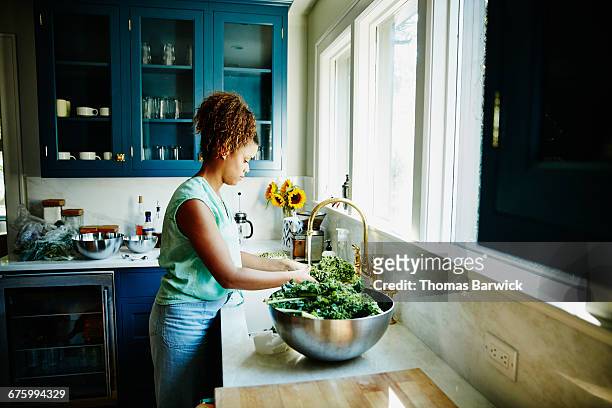 Woman washing organic kale in kitchen sink