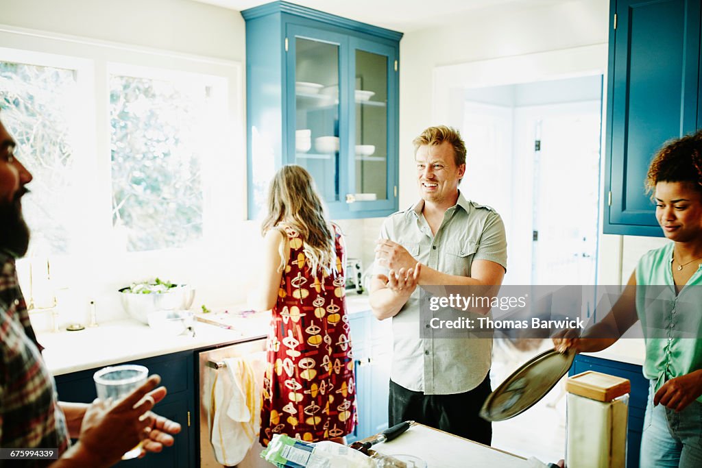 Man preparing dinner with friends in kitchen