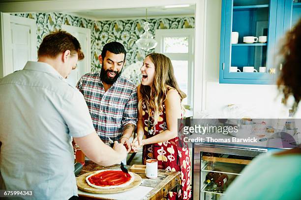 laughing couple preparing pizza with friends - dinner party at home stock pictures, royalty-free photos & images