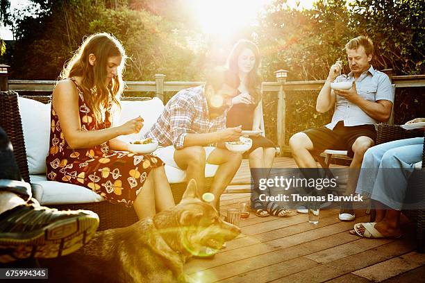 friends eating dinner together on backyard deck - dinner on the deck stock pictures, royalty-free photos & images