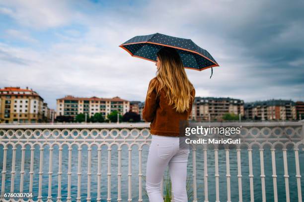 young woman holding an umbrella - mirar el paisaje stock pictures, royalty-free photos & images