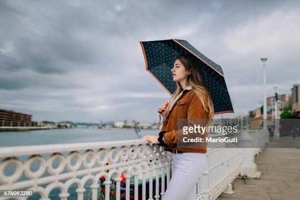 giovane donna in possesso di un ombrello - vestimenta foto e immagini stock