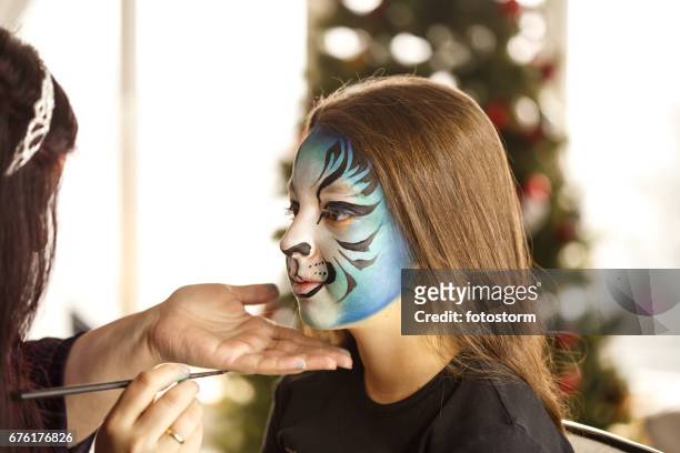 meisje krijgen een gezicht schilderen bij kerstfeest - geschminkt gezicht stockfoto's en -beelden
