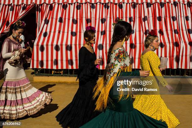 Woman wearing a traditional Sevillana dress looks on at the Feria de Abril on May 2, 2017 in Seville, Spain. The Feria de Abril, which has a story...