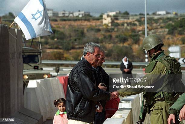 Palestinians show their identity documents at an Israeli Defense Forces check point December 6, 2001 while trying to get back into Bethlehem. The...