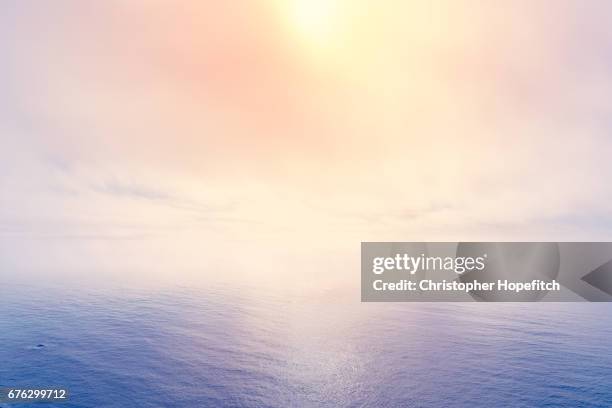 sun breaking through sea fog - dawn sky stock-fotos und bilder