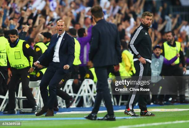 Zinedine Zidane head coach of Real Madrid celebrates as Cristiano Ronaldo of Real Madrid scores their second goal as Diego Simeone manager of...