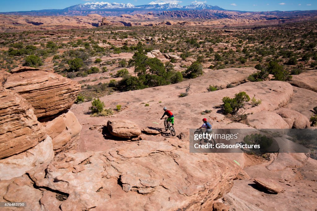 A man leads a woman on a cross-country mountain bike trail ride in Moab, Utah, USA.